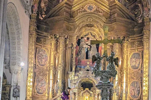 El retablo dorado del templo iluminado, con el paso del Nazareno delante.